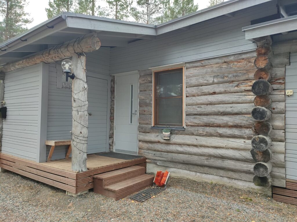 hirsimökin ulko.-ovi valkoinen pysty lasiaukolla ja vaakaura kuviolla