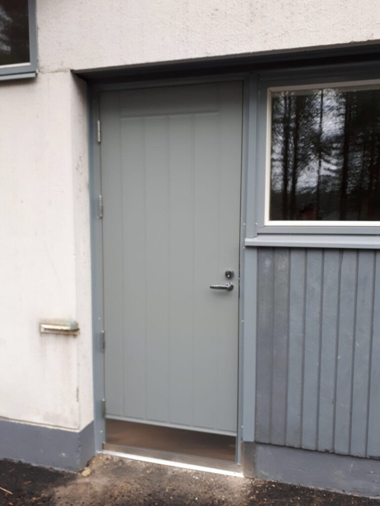 harmaa umpinainen ulko-ovi pystyura kuviolla ja potkulevyllä